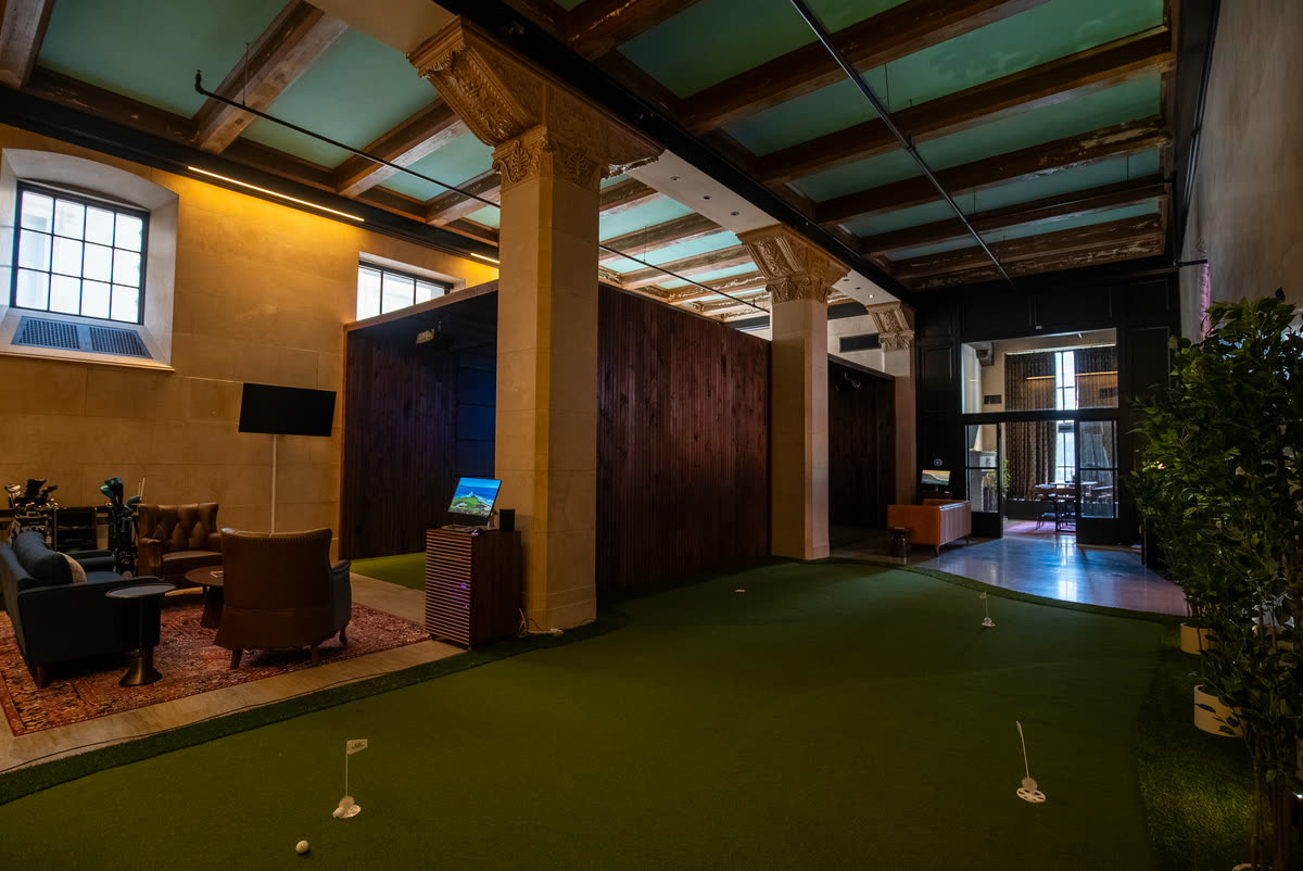 The putting green beneath the carved columns at Philadelphia Golf Club